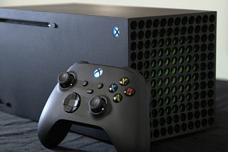 Xbox Series X console positioned horizontally with an Xbox controller leaning on it. How PlayStation Won 2020.