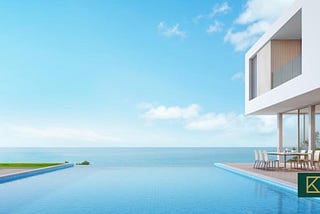 The image showcases a stunning luxury real estate property overlooking the vast ocean. The property features a spacious terrace with an infinity pool that blends seamlessly with the azure waters. Tropical vegetation surrounds the property, adding to the serene ambiance. The clear blue skies overhead create a perfect backdrop, enhancing the beauty of this idyllic setting.
