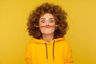 Picture of young woman with curly hair and a pencil under her nose