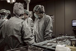 A team of surgeons clustered tightly around a patient during operation
