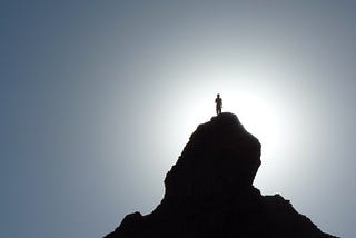 Silhouette of a hiker at the top of a mountain