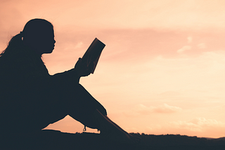 A girl reading a book outside.