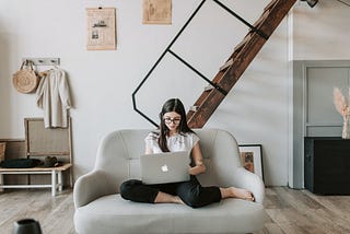 A woman browsing on her laptop sitting on a sofa