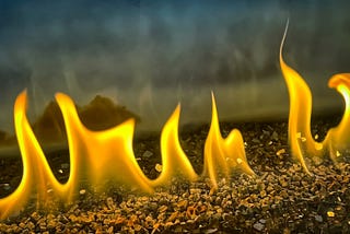 flames in a row rise from a gravel surface
