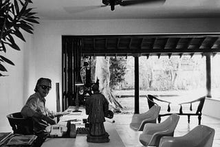 A picture of Geoffrey Bawa sitting in his tropical modernist fashioned office and the courtyard area is visible in this image.