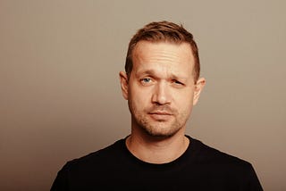 Man in a black t-shirt looking comically pensive