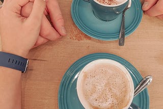 A couple holding hands while having coffee.