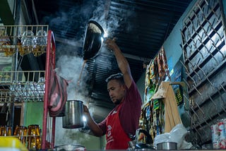 A barista in Acehnese coffee house is brewing the coffee for about 25 people.