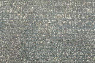 The Rosetta Stone, an ancient Egyptian artifact, featuring inscriptions in three scripts: hieroglyphic, demotic, and Greek. This stone was crucial in deciphering Egyptian hieroglyphs, as scholars could compare the identical text across the three scripts to unlock their meaning.