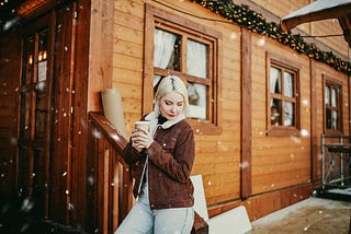 A lady on a sidewalk, holding a cup of coffee