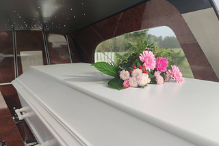 A coffin with flowers on the lid in a hearse