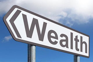 Black on White arrow-shaped sign reading “Wealth” against a blue sky with white clouds.