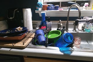 A sink and counter full of dirty dishes that are still molding in the author’s house.