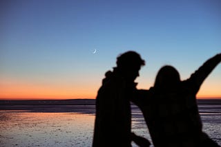 A silhouette of couple at the beach during sunset
