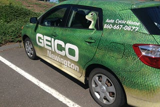 Geico Faces $2M Settlement Over Unpaid Replacement Fees — Geico logo car