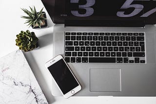 A smartphone sitting on top of an opened laptop.