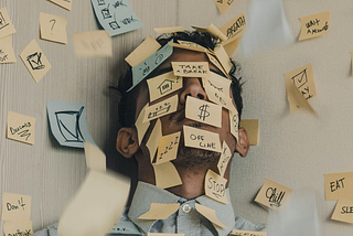 Young man covered in sticky notes, work overload