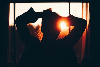 Woman looking at sun through window
