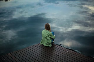 woman sitting by a river