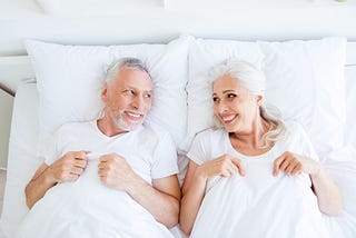A mature couple in bed and pleased with themselves.