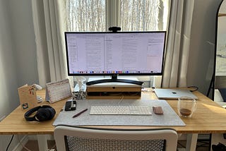 a photo of the author’s desk and computer monitor showing first draft and second draft side by side