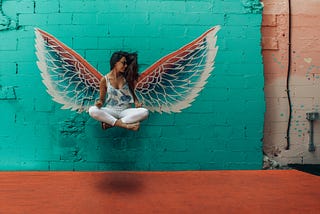 Woman levitating foreground. Angle wings graphic in background.