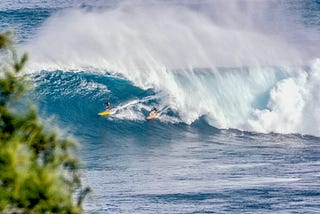 surfers under a wave