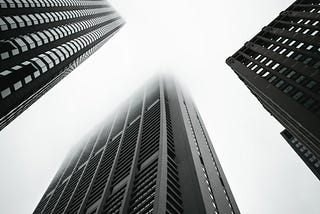 Tall buildings rise into the sky. Black-and-white photo.