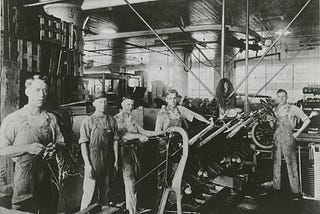 Grease-stained factory workers building engines, circa 1925