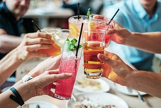 Several hands holding cocktail glasses, making a toast.