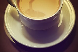 Coffee with cream in a white cup on a white saucer