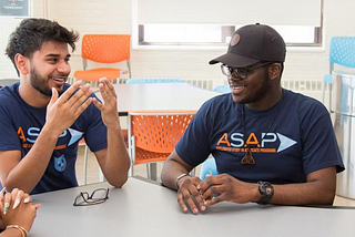 Group of students wearing ASAP t-shirts sit around a table.