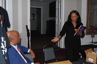 Dominic Carter sitting listening as his daughter Courtney Carter speaks at a public event focused on child advocacy, resilience, and community support.