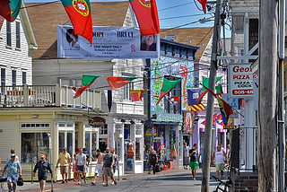 A picture of the streets in Provincetown during the Portuguese American Festival with 10 large Portuguese flags hanging across the street.