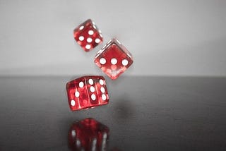 Three red dice bouncing of a black table