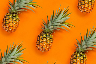 Composição visual com abacaxis enfileirados na diagonal sobre fundo laranja.