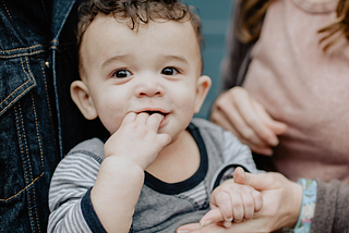 Toddler holding hands with caregiver.