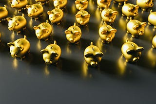Several gold piggy banks lined up in rows on a black counter-top surface.