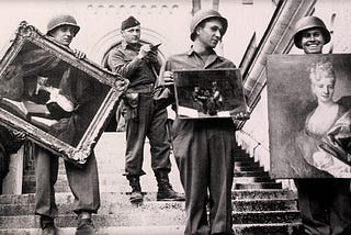 Four Monuments Men on the steps of a palace. Three are holding recovered artwork.