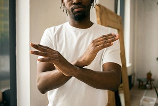 Faceless black man showing stop gesture with crossed hands