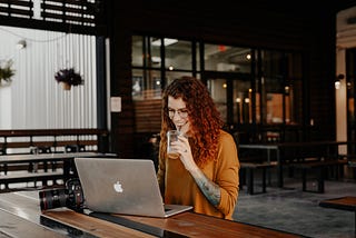 A person using a mac lapton while drinking a beverage.