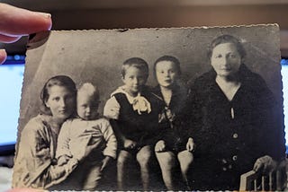 a photo of an old family photograph, with author’s great grandma, grandma, and father, uncle and aunt as children