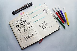 A photo of an open journal with the message "make the world a pretty place"