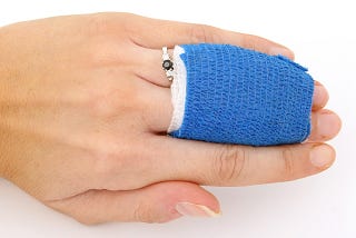 A women’s hand with two fingers wrapped in gauze to heal.