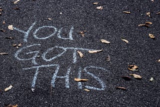 You Got This written in chalk on asphalt with small leaves scattered around.