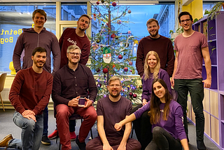 The Beining & Bogen team posing in front of a christmas tree at the office.