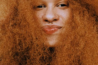 Black woman with big red hair, smiling at camera