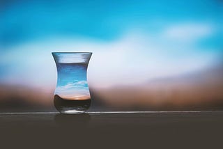 A photo of a curved glass of water capuring the blur of a sunset