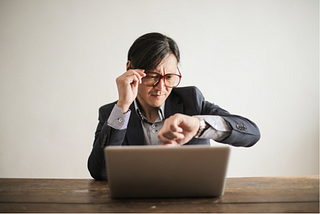 Lawyer looking on watch while working on laptop