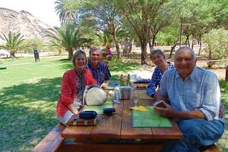 Author and smiling others seated at table at an oasis in the Namib desert